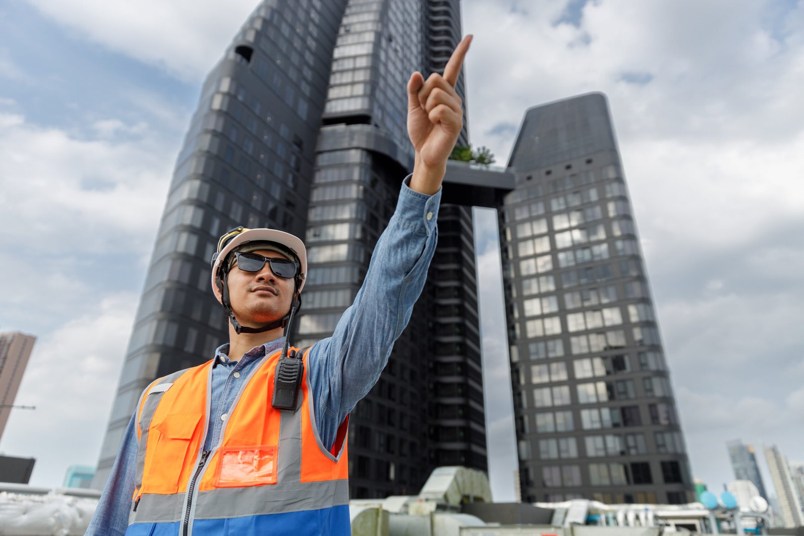 Man Industrial engineer with walkie talkie pointing working at rooftop construction. Male technician working checking HVAC system building factory. Installing large air conditioning system.